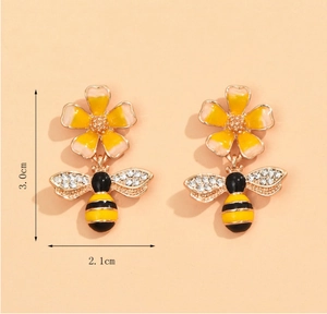 Detail view of flower and bee drop earrings with crystals and yellow enamel finish
