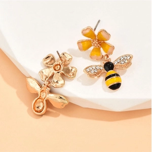 Elegant floral bee stud earrings featuring yellow petals and crystal wings on white props