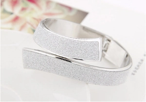 Detail of silver crossover wide cuff bracelet with a frosted sandblasted starlight texture