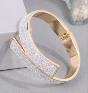 Detailed view of the gold-plated hinged bracelet with silver glitter frosted finish