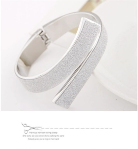 Detail of silver crossover bangle featuring a sparkling frosted sandblasted texture