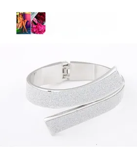 Close-up of silver wide crossover bangle with sparkling frosted finish and hinge closure