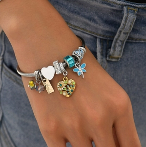 Detail of a DIY charm bracelet with blue dragonfly and golden heart beads on the wrist