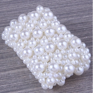 Elegant wide stretch bracelet featuring woven white pearls in various sizes on wood