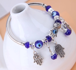 Dettaglio di ciondoli Mano di Fatima e Occhio di Allah su bracciale rigido etnico