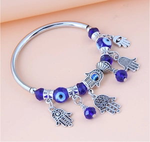 Dettaglio dei ciondoli mano di Fatima e perle blu scuro su un bracciale in metallo argento