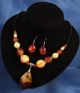 Detail eines Vintage-Harz-Schmucksets mit bernsteinfarbenen Perlen auf schwarzem Samtständer