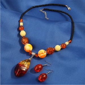 Elegantes Set aus Bernstein-Harz Halskette und Ohrringen auf luxuriösem Seidenhintergrund