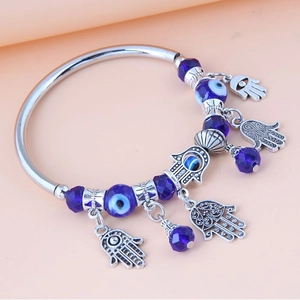 Bracciale argentato con ciondoli Mano di Fatima, Occhio di Allah e perle blu su fondo neutro