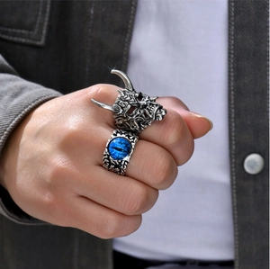 Detail of men's punk rings featuring a silver skull and a bright blue evil eye gemstone