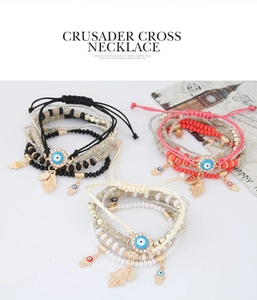 Détail de bracelets perlés multicouches avec breloques œil et main de Fatma sur fond blanc