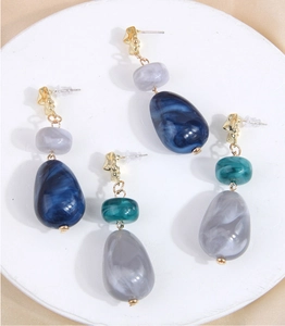 Macro shot of elegant long earrings with marble resin beads and golden irregular metal studs