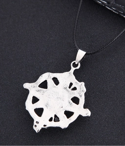 Macro view of retro silver compass pendant with antique finish and cutout details