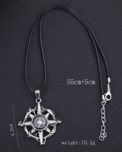 Macro shot of silver compass pendant with vintage black engraving on black cord