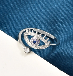 Detail of evil eye ring with blue and purple zircons on a dark blue satin background