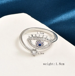 Detail of silver evil eye ring with blue crystal and zircons on blue silk background