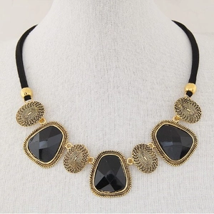 Collier doré audacieux avec gemmes noires irrégulières et détails en relief texturé