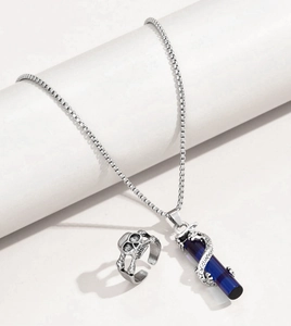 Gothic silver dragon pendant with blue crystal and carved skull ring set on white stage
