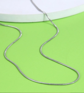 Close-up of minimalist silver snake chain necklace on a curved display surface