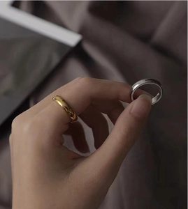 Close-up of minimalist polished gold and silver stainless steel rings on hand