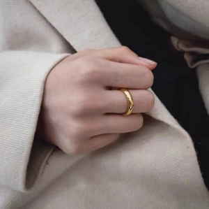 Close-up of a minimalist gold polished stainless steel band ring worn by a model