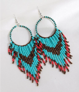 Detail of bohemian tassel earrings with turquoise and red beads on silk fabric