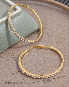 Detail of 5.3cm gold hoop earrings with white rhinestones and a secure clasp closure