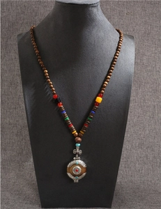 Détail du collier ethnique en perles de bois avec pendentif vintage en métal sur mannequin