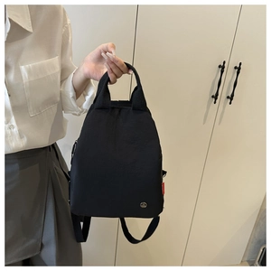 Detail of minimalist black nylon backpack featuring fabric texture and metallic logo
