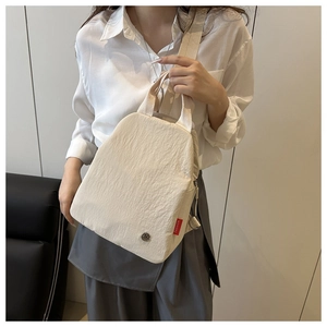 Detail of off-white textured backpack with FASHION label and metal buckle shown on model