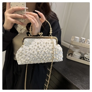 Dettaglio borsa vintage in pizzo bianco con perle, manico dorato e tracolla a catena