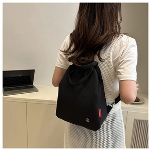 Detail of minimalist black nylon backpack with fashion tag and silver metal logo
