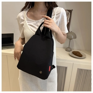 Detail of multi-functional black mini backpack with red fashion tag and metal logo