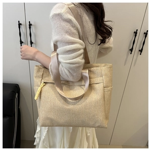 Detail view of woven striped tote bag showing durable champagne gold nylon shoulder straps