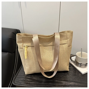 Modieuze beige geweven tote tas met schouderbanden en decoratieve gele bedel