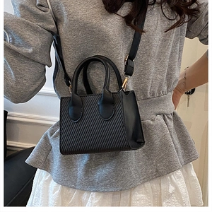 Detailed look at the black woven crossbody bag with gold hardware on a female model