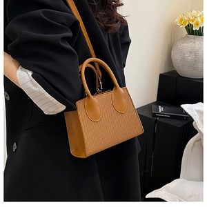 Brown woven texture crossbody bag styled with a black blazer in a chic urban setting