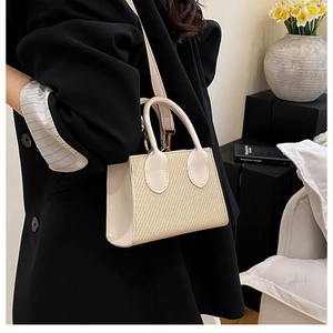 Detail of beige straw woven crossbody bag with leather trim and adjustable shoulder strap