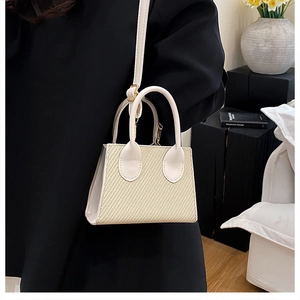 Chic cream leather crossbody bag with woven texture panel and top handles for summer fashion