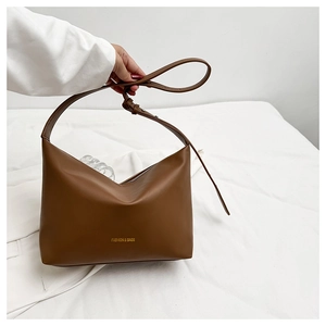 Détail du sac hobo en cuir mat marron avec lettrage doré et fermeture éclair métallique robuste