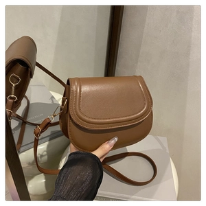 Detail of caramel brown saddle bag showing gold D-ring hardware and fine stitching