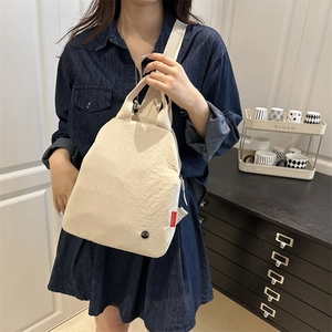 Versatile cream-white fabric backpack for women with red fashion label and wide strap