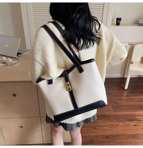 Rear view of a model wearing the cream and black contrast tote bag with gold clasp