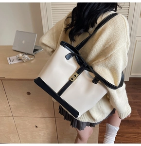 Detail of a large cream tote bag with black contrast trim and a gold twist-lock buckle
