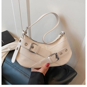 Detail of cream leather shoulder bag with decorative buckles and silver eyelets