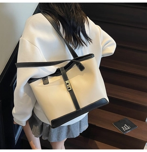 Close-up of contrast stitch leather tote bag with gold twist lock on wooden stairs