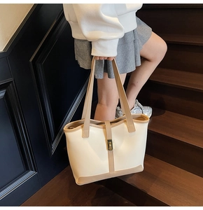 Detail of trendy large tote bag with beige khaki stitching and golden metal clasp