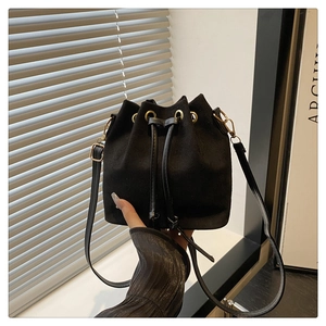 Detail of black suede bucket bag featuring drawstring closure and gold metal eyelets