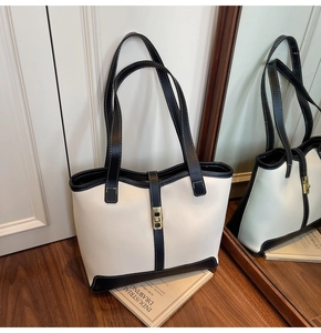 Vue détaillée du grand sac cabas bicolore crème et noir posé sur un parquet en bois