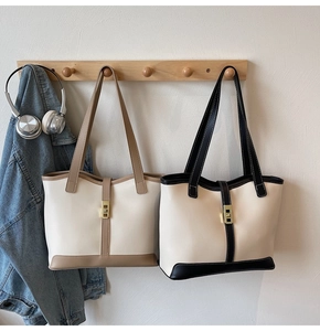 Detail of color-block tote bags with metal buckles hanging in a minimalist setting